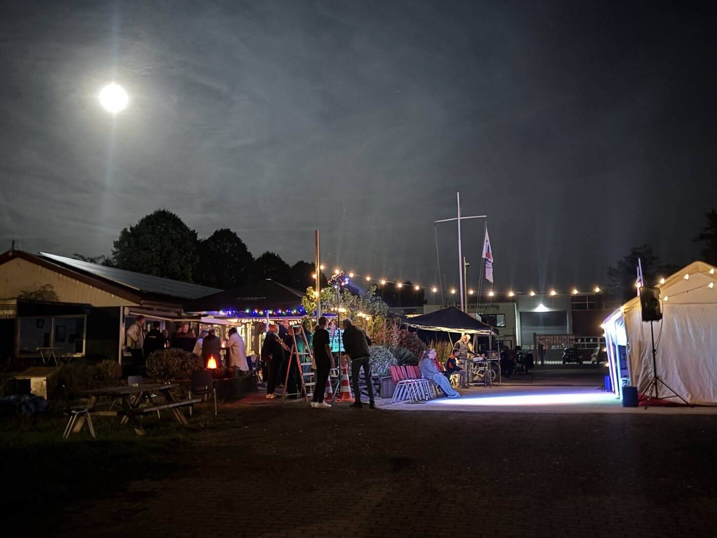 Leden genieten van een zomeravond op de haven, met verlichting, muziek en de volle maan
